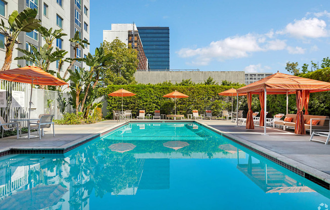 A swimming pool surrounded by orange umbrellas and lounge chairs.