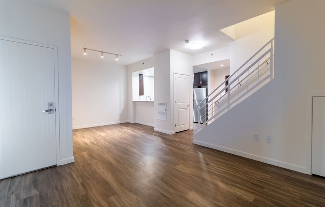 an empty living room with white walls and wood floors and a staircase