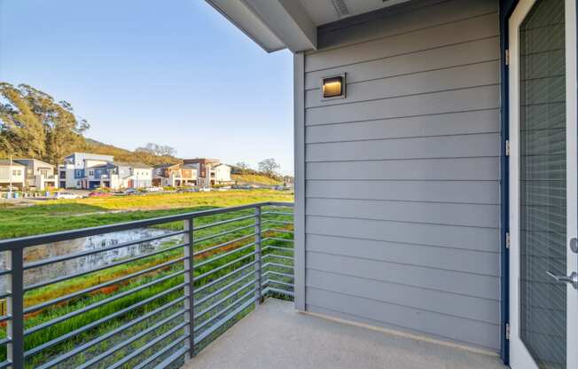 the view from the balcony of a house looking out onto a yard and a river