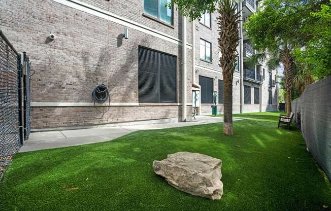 the yard of a building with a rock on the grass