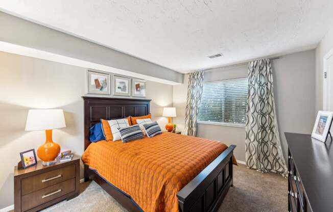 A bedroom with a bed, nightstand, and window.