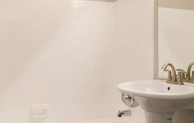 a white bathroom with a sink and a bath tub