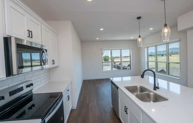 a kitchen with white cabinets and black appliances and white counter tops at The Crossings at Windsong, Prescott Valley, Arizona