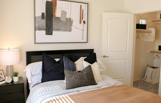 A bedroom with a large bed and a painting above it.