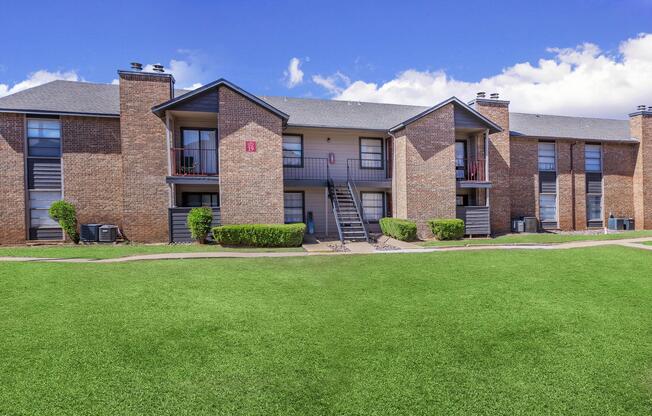 a large brick building with green grass in front of a house