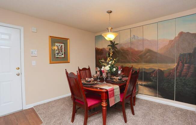 a dining room with a table and chairs and a painting on the wall