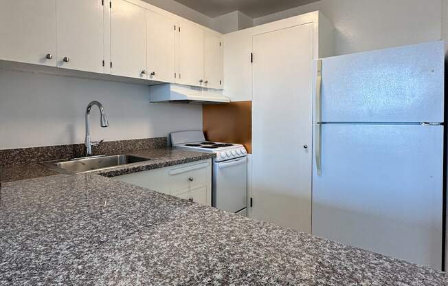 an empty kitchen with granite counter tops and white appliances