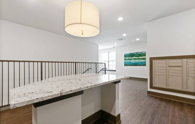 a white kitchen with a marble counter top and a staircase