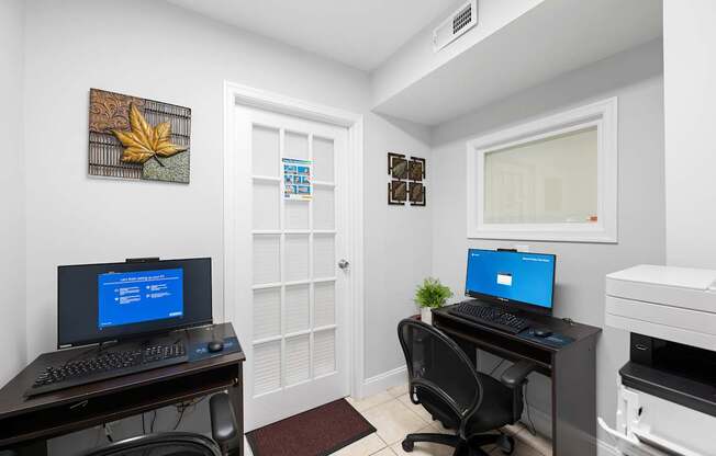 a home office with two computers and a printer