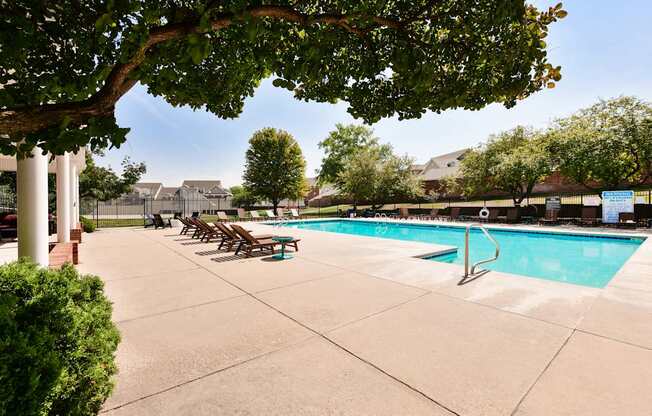 A pool surrounded by trees and chairs.