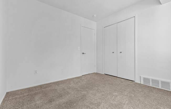 a bedroom with white walls and carpet