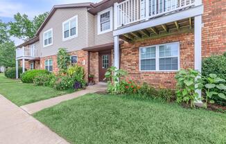 a house with a lawn in front of a brick building