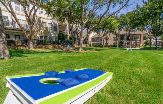 a blue and green trampoline in a grassy area with apartment buildings in the background