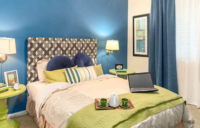 a bedroom with blue walls and a bed with a laptop on it