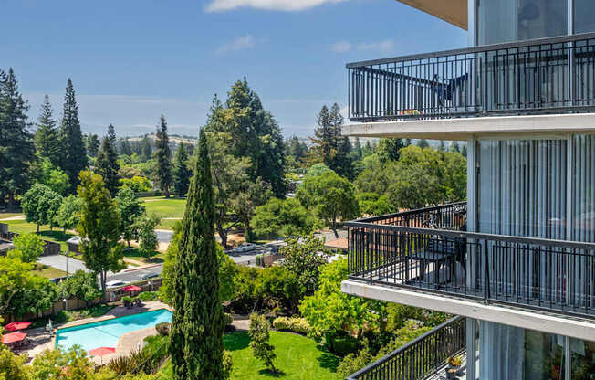 A balcony overlooks a pool and a lush green landscape.