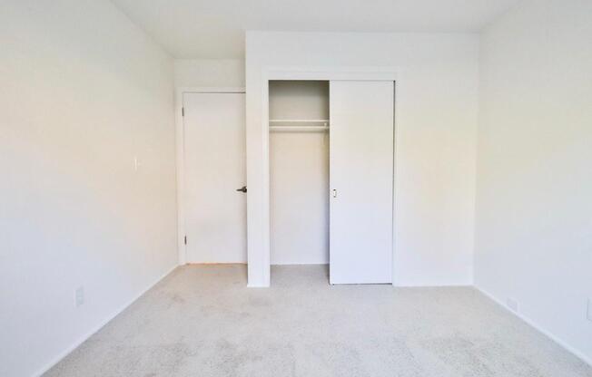 an empty room with white walls and closet doors
