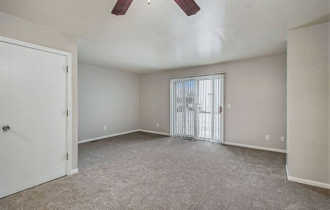 an empty living room with a sliding glass door to a patio