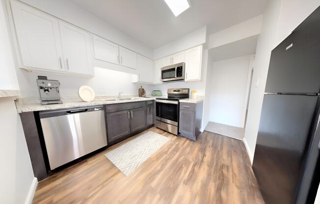an empty kitchen with stainless steel appliances and white cabinets