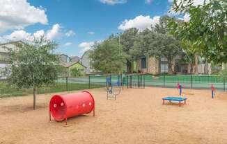 a playground with a seesaw and a bench in front of houses