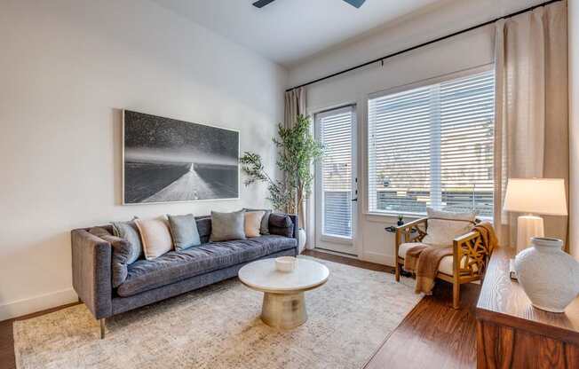 A living room with a grey couch, a white coffee table, and a painting on the wall.