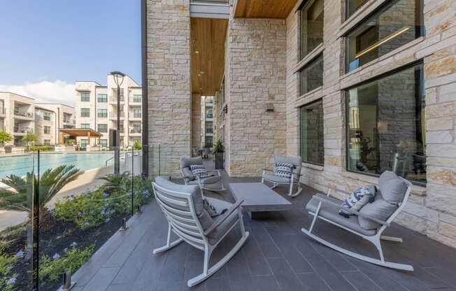 Lenox SoCo Apartments patio with two chairs and a table and a pool