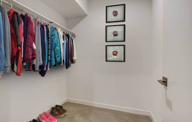 a walk in closet with clothes hanging on a rack and shoes on the floor