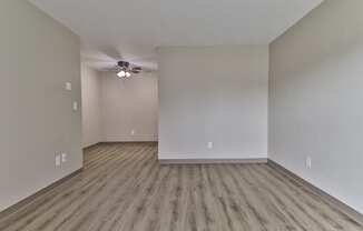 an empty living room with hardwood floors and a ceiling fan