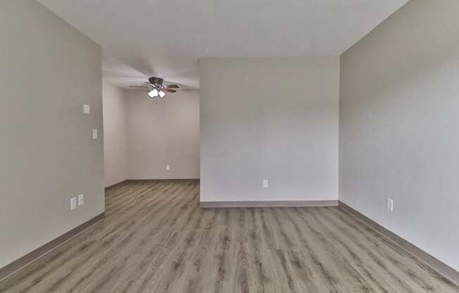 an empty living room with hardwood floors and a ceiling fan