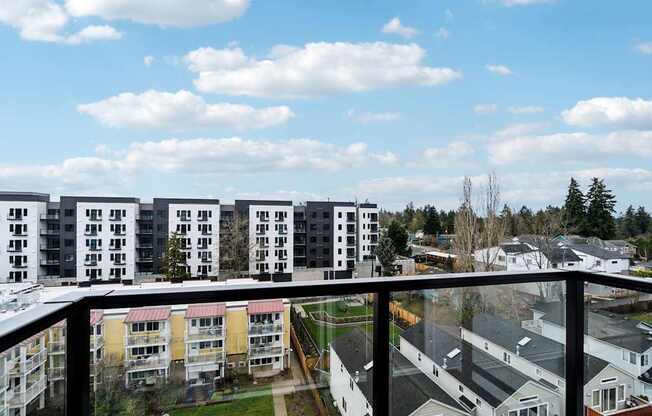 A view from a balcony overlooking apartment buildings and a parking lot.