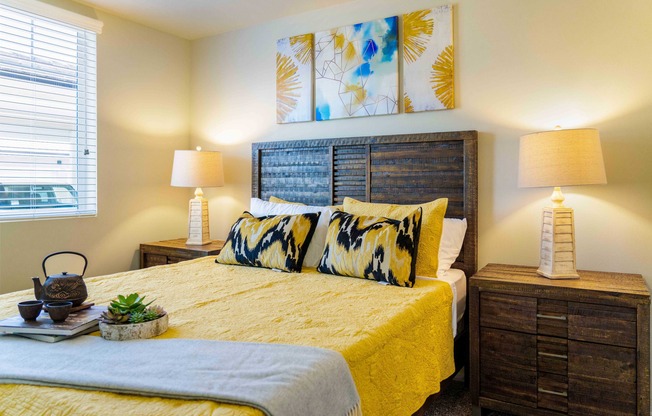 bedroom with nightstands and bed with yellow comforter and pillows at Turtle Creek apartments