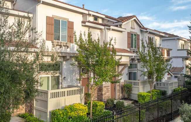 A row of houses with a black fence in front.