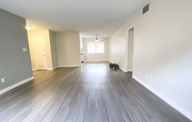 an empty living room with wood floors and white walls