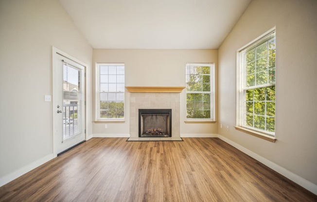 an empty living room with a fireplace and wood flooring