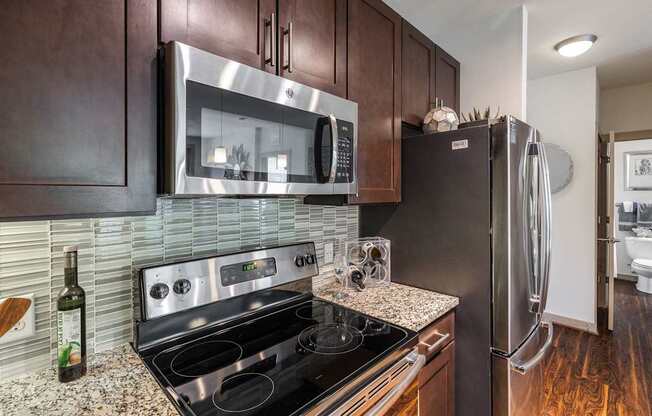 A modern kitchen with dark wood cabinets and stainless steel appliances.