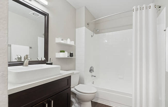 Model Bathroom with Dark Wood Cabinets, Wood-Style Flooring and Shower/Tub at Horizon Apartments located in Santa Ana, CA.