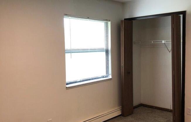 an empty room with a window and a closet