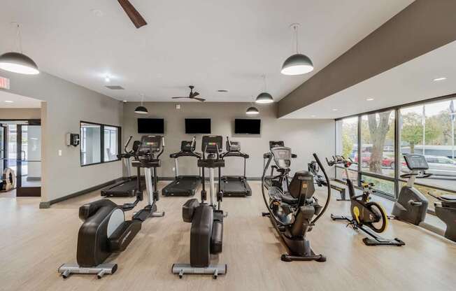 A gym with a variety of exercise equipment including treadmills, stationary bikes, and elliptical machines.