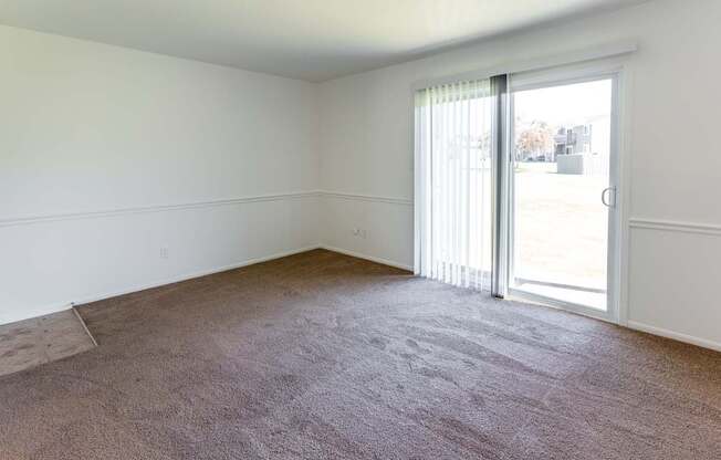 an empty living room with a sliding glass door to a patio