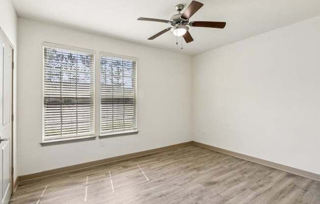 A room with a ceiling fan and a window with blinds.