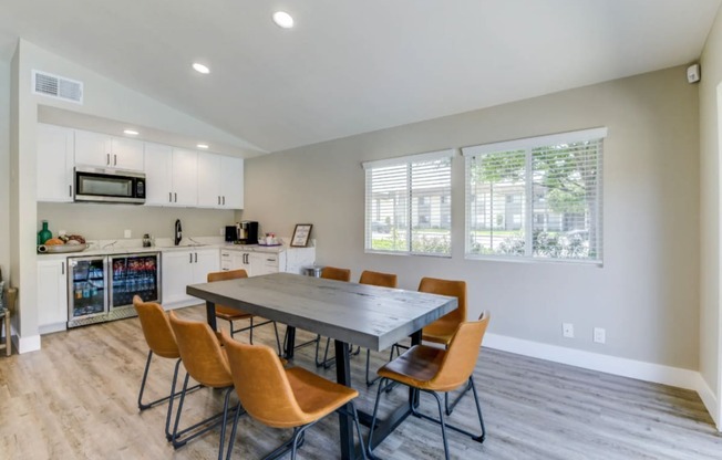 a dining area with a table and chairs and a kitchen in the background