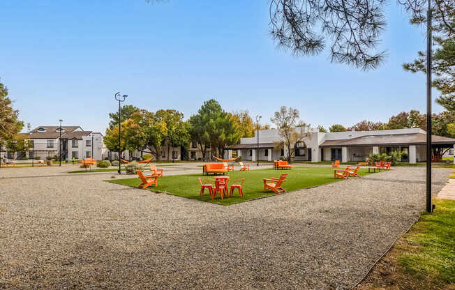 a park with orange tables and chairs on the grass