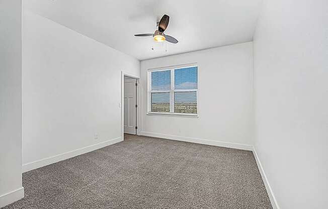 bedroom with a large window and ceiling fan at Trade Winds Apartment Homes, Elkhorn, NE