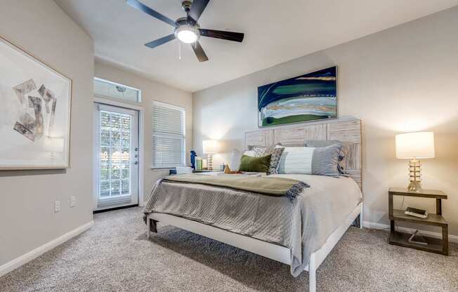 A bedroom with a bed, nightstand, and a ceiling fan.