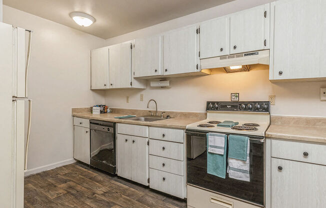 a kitchen with white cabinets and a stove and a sink