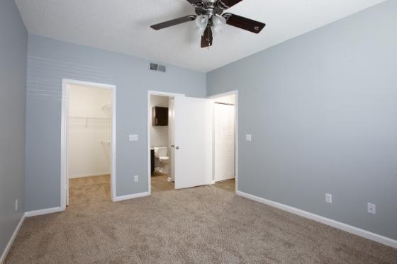A room with a ceiling fan and carpeted floor.