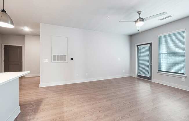 an empty living room with a ceiling fan and a window