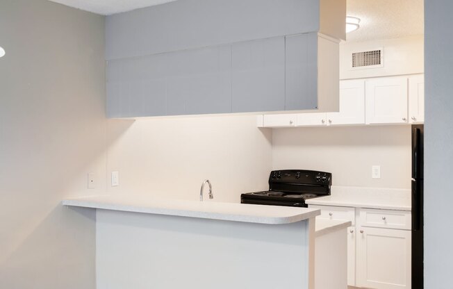 a kitchen with white cabinets and a black stove