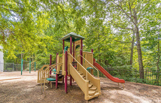 A playground with a red slide and a green roof.