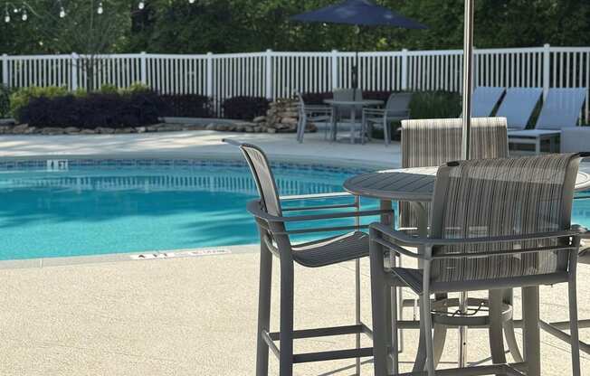 A poolside table with chairs and an umbrella.