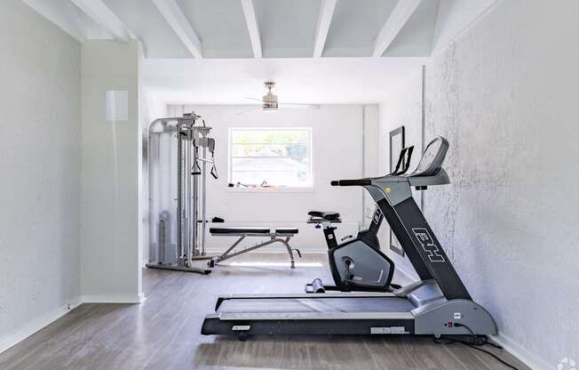 A treadmill is in a room with a window.